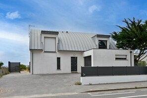 A modern two-story building with a flat roof, a black door, and a gated entrance. - Le Cara - Situé en front de mer (La Turballe)