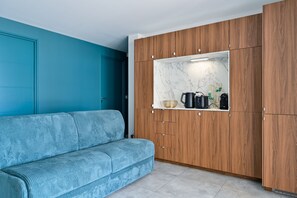 A modern kitchen with wooden cabinets, a marble countertop, and a blue sofa. - Le Cara - Situé en front de mer (La Turballe)