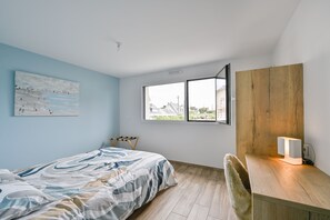 A bedroom with a bed, a desk, a chair, a window, and a painting on the wall. - Le Cara - Situé en front de mer (La Turballe)