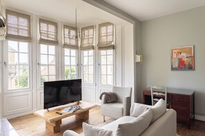 Un salon avec un téléviseur, un canapé et une table basse en bois.
