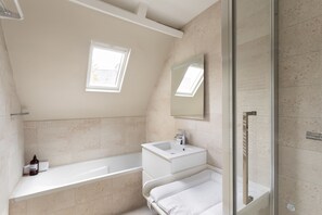Une salle de bain moderne équipée d’une baignoire, d’un lavabo, d’un miroir et d’un espace douche.