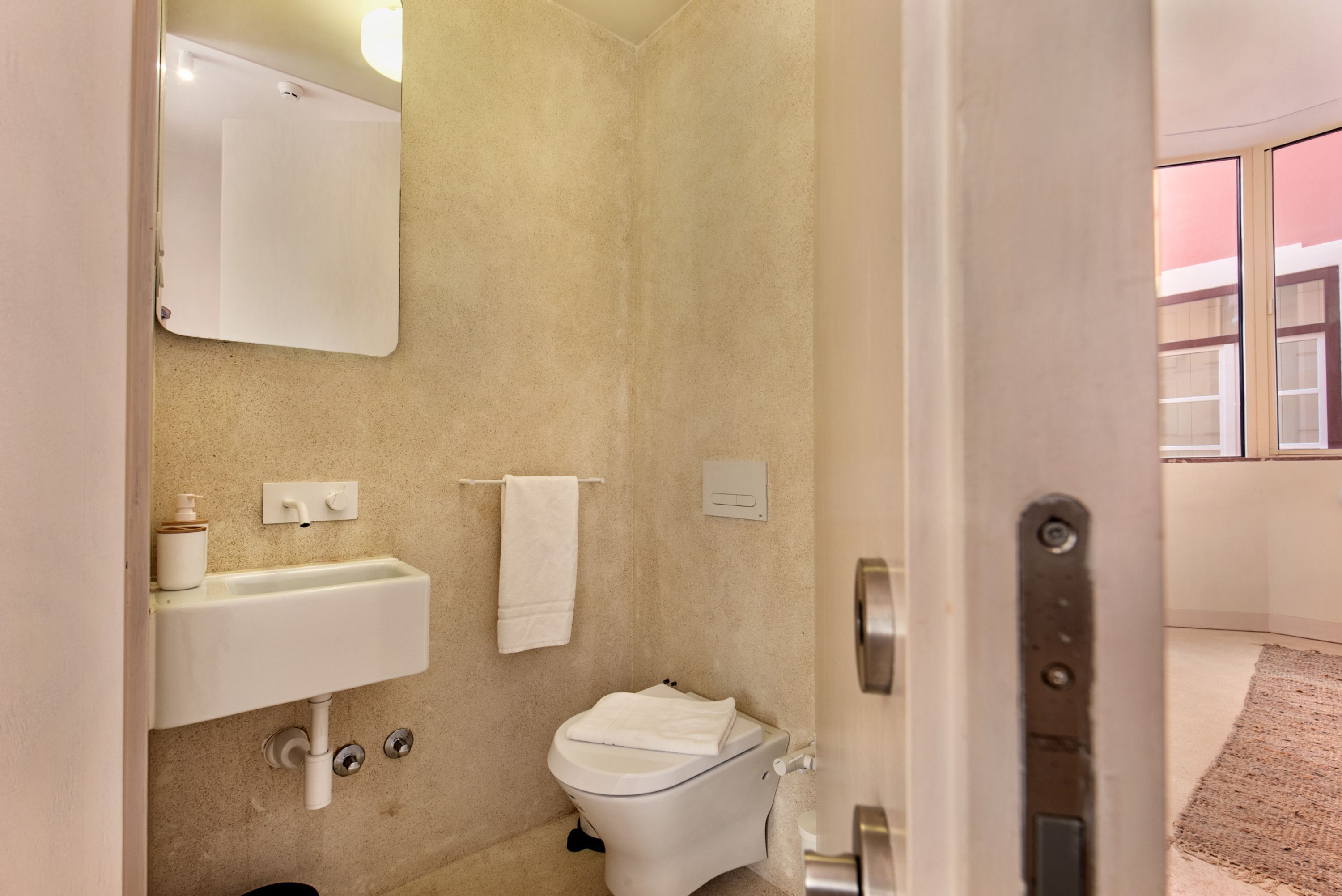 A bathroom with a sink, toilet, and mirror.