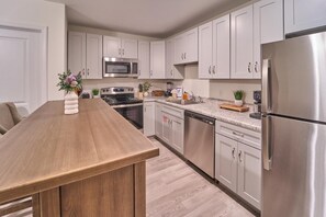 Una cocina moderna con armarios blancos, electrodomésticos de acero inoxidable y una isla de madera.