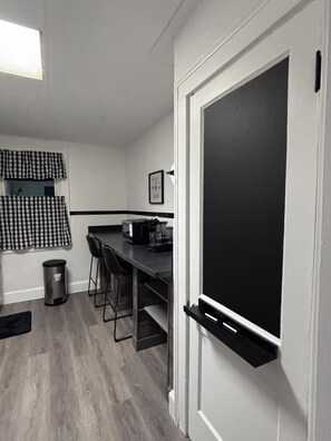 A compact kitchen with a black countertop, a microwave, and a coffee maker. There is a trash can and a black chair. - Modern Top Level Escape - Stylish, Clean and Central (Cincinnati)