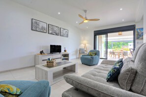 Ein modernes Wohnzimmer mit einer Couch, einem Couchtisch, einem Fernseher und Kunstwerken an der Wand.