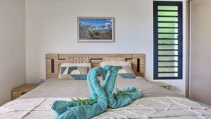 Un letto rifatto con cura, un'elegante disposizione di asciugamani, una cornice con un'immagine e una finestra con persiane.