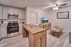 A kitchen with white cabinets, a microwave, a stove, and a ceiling fan. - The Ruby 306 (Pigeon Forge)