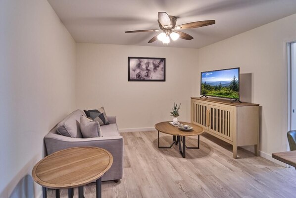 A living room with a sofa, a coffee table, a TV on a cabinet, and a ceiling fan. - The Ruby 307 (Pigeon Forge)