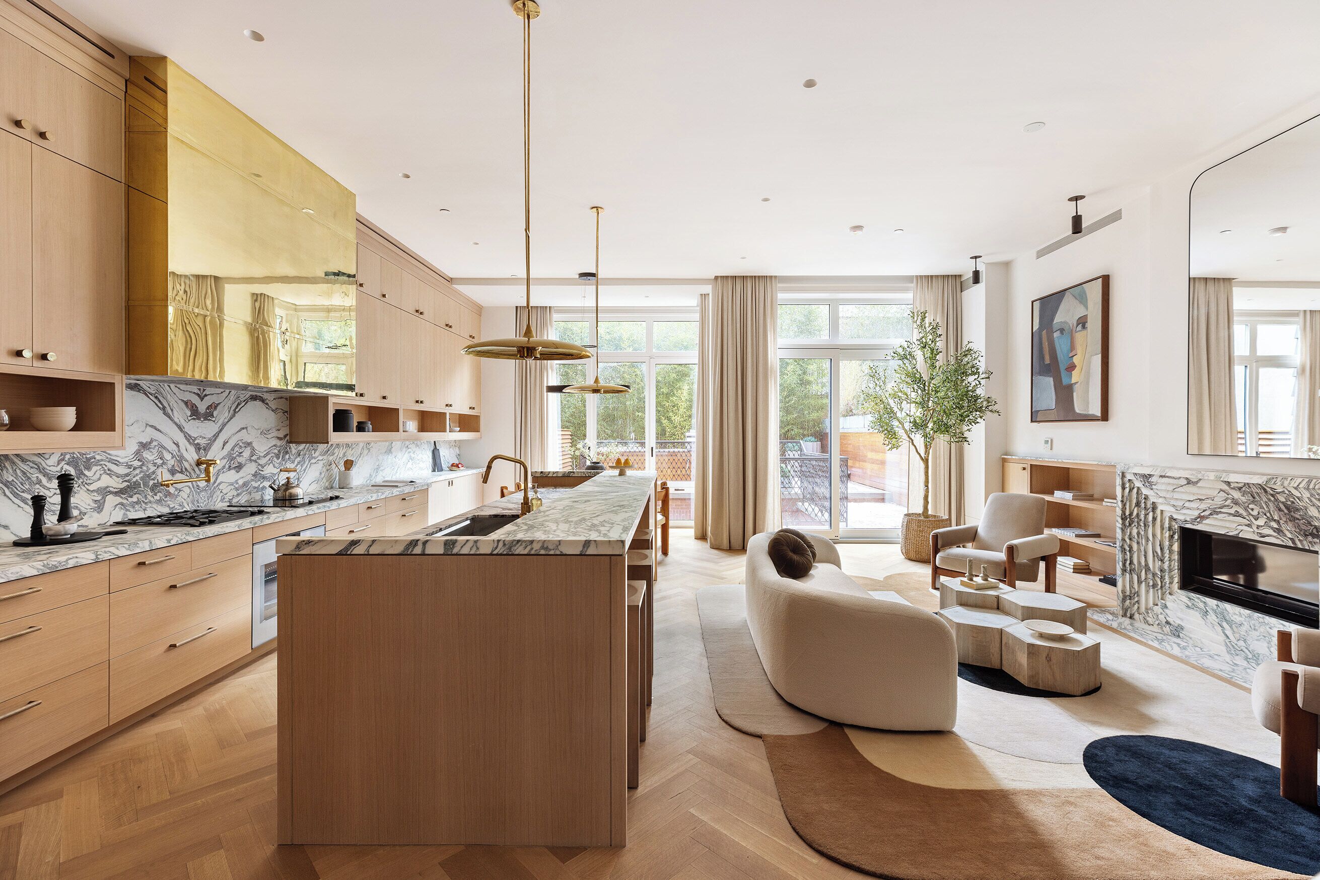 Une cuisine moderne dotée d’un îlot en marbre, de meubles en bois et de luminaires suspendus.