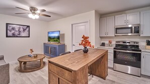 A modern kitchen with a wooden island, stainless steel appliances, and a ceiling fan. - The Ruby 308 (Pigeon Forge)