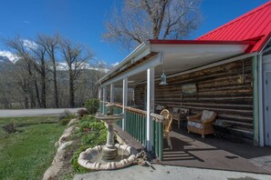 A rustic log cabin with a porch, a stone fountain, and a chair outside. - Biggest Twin Lakes lodge room, sleeps 4 - private bath, entrance & lake views (Twin Lakes)