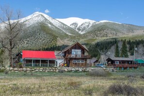 A wooden cabin with a red roof, a large wooden structure with a balcony, and a windmill in a mountainous area. - Biggest Twin Lakes lodge room, sleeps 4 - private bath, entrance & lake views (Twin Lakes)