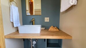 Een badkamer met een houten wastafelmeubel, een witte wastafel, een spiegel en een handdoekhouder.