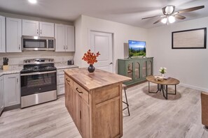 A kitchen with a wooden island, stainless steel appliances, a green cabinet, and a small round table with a vase. - The Ruby 309 (Pigeon Forge)