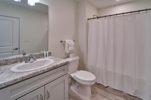 A bathroom with a sink, toilet, and shower curtain. - The Ruby 309 (Pigeon Forge)