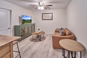 Una sala de estar con televisor, un mueble verde, un sofá marrón y una mesa de madera.