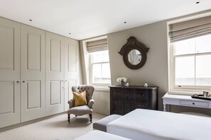 Ein Schlafzimmer mit Bett, Kommode, Stuhl und Kleiderschrank.