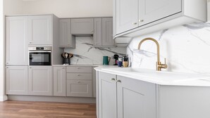 Une cuisine moderne avec des meubles gris, un plan de travail en marbre blanc et un robinet doré.