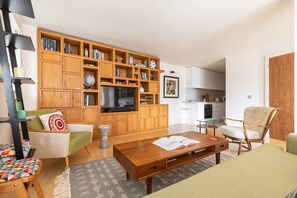 A living room with a wooden bookshelf, a television, a sofa, and a coffee table. - Hardwick Street III - Two Bedroom Apartment, Sleeps 4 (London)