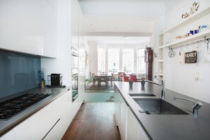 Eine moderne Küche mit einer zentralen Kochinsel, einem Essbereich mit Tisch und Stühlen sowie einer Küchenarbeitsplatte mit Spüle und Armatur.