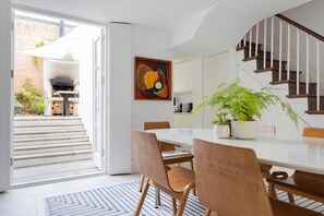 Eine offene Küche mit Essbereich, einer Treppe und einem großen Gemälde an der Wand.