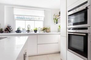 Eine moderne Küche mit weißen Schränken, einem eingebauten Ofen und einem Fenster mit Blick auf die Stadt.