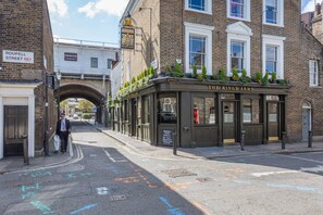 Eine Kneipe namens 'The King's Arms' mit einer traditionellen Fassade, einem Backsteinbogen und einem Schild mit der Aufschrift 'Roupell Street SE1'.