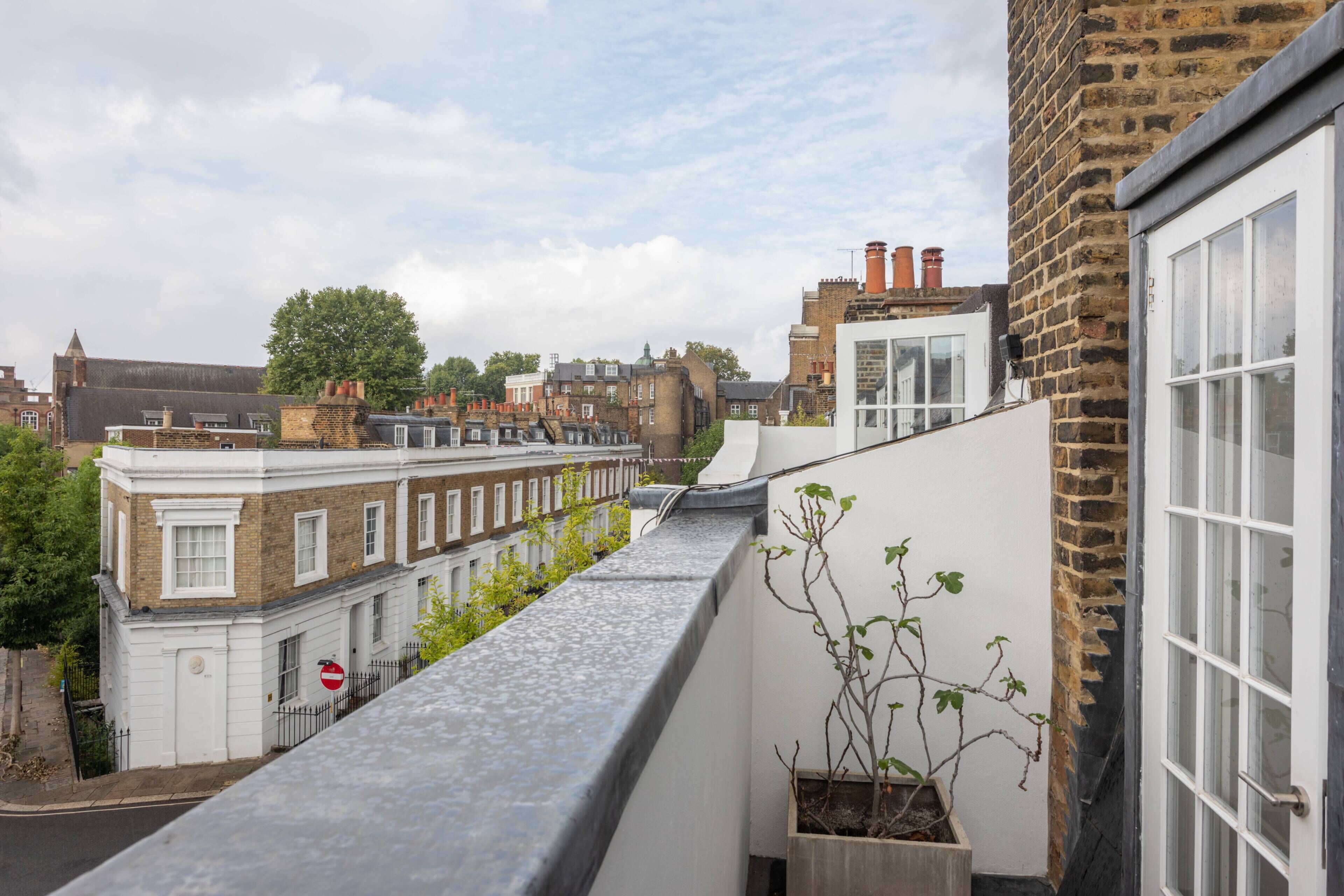 A rooftop terrace with a view of adjacent buildings, a potted plant, and a 'no entry' sign.