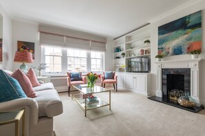 Ein Wohnzimmer mit Sofa, Couchtisch, Kamin und Regalen mit Dekoration.