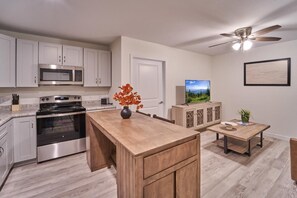 A modern kitchen with stainless steel appliances, a wooden island, and a dining area with a table and chairs. - The Ruby 310 (Pigeon Forge)