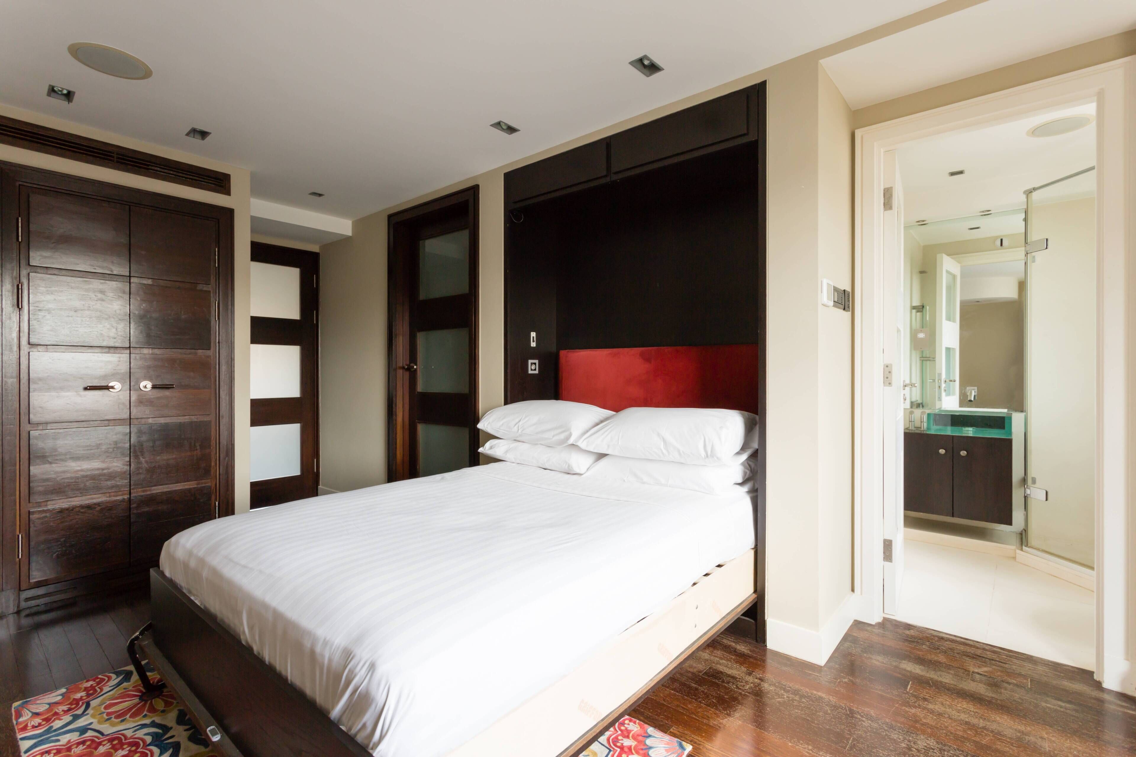 Una camera da letto con un letto, un armadio e un bagno parzialmente visibile attraverso una porta aperta.