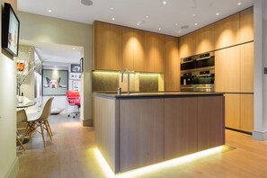 A modern kitchen with wooden cabinets, a central island, and built-in appliances. - Regent's Park South - Two Bedroom Apartment, Sleeps 4 (London)