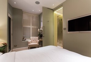 A bedroom with a bed, a chair, a vanity, and a shower area. - Regent's Park South - Two Bedroom Apartment, Sleeps 4 (London)