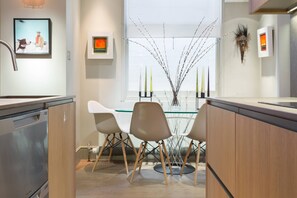A modern kitchen with a glass dining table, wooden cabinets, and a decorative vase. - Regent's Park South - Two Bedroom Apartment, Sleeps 4 (London)