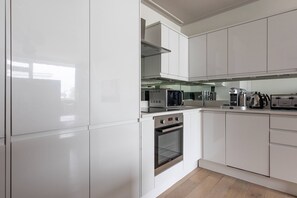 Eine moderne Küche mit weißen Schränken, Edelstahlgeräten und einem eingebauten Backofen.