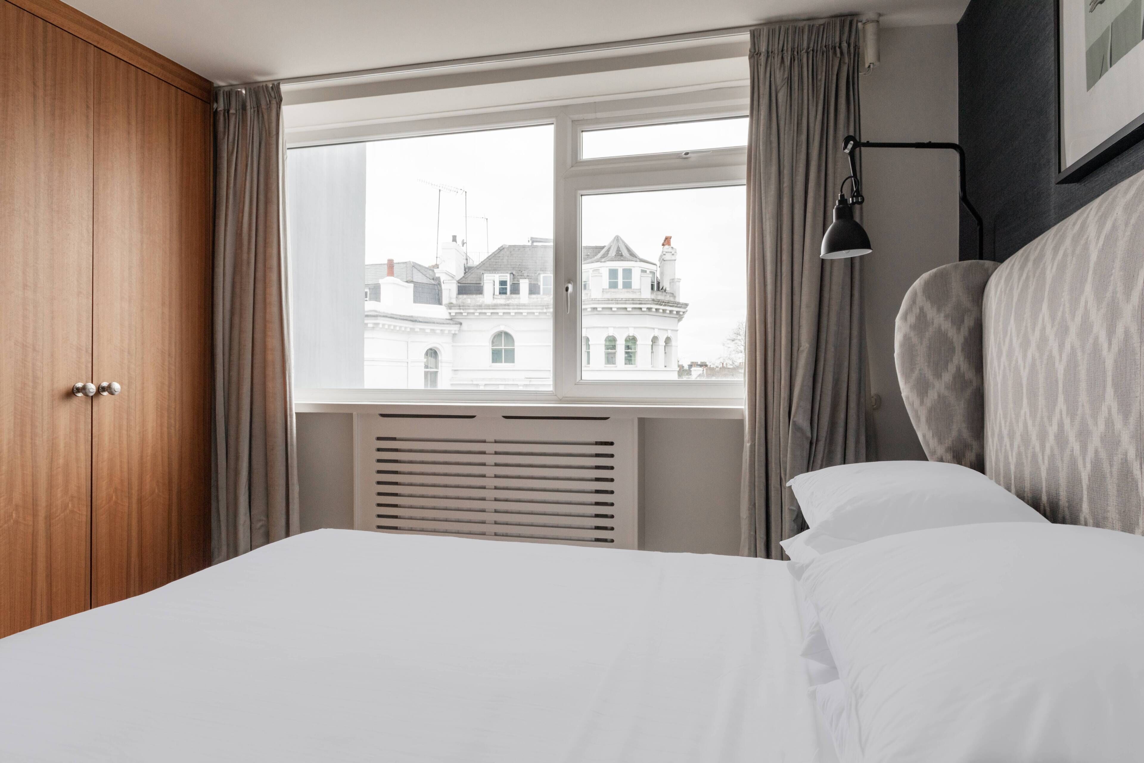 Ein Hotelzimmer mit großem Fenster, einem Bett, einem Kleiderschrank und einer Heizung.