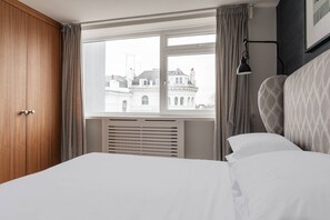 Ein Hotelzimmer mit großem Fenster, einem Bett, einem Kleiderschrank und einer Heizung.