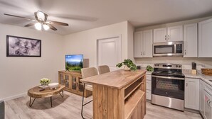 A modern kitchen with a wooden island, stainless steel appliances, and a ceiling fan. - The Ruby 311 (Pigeon Forge)