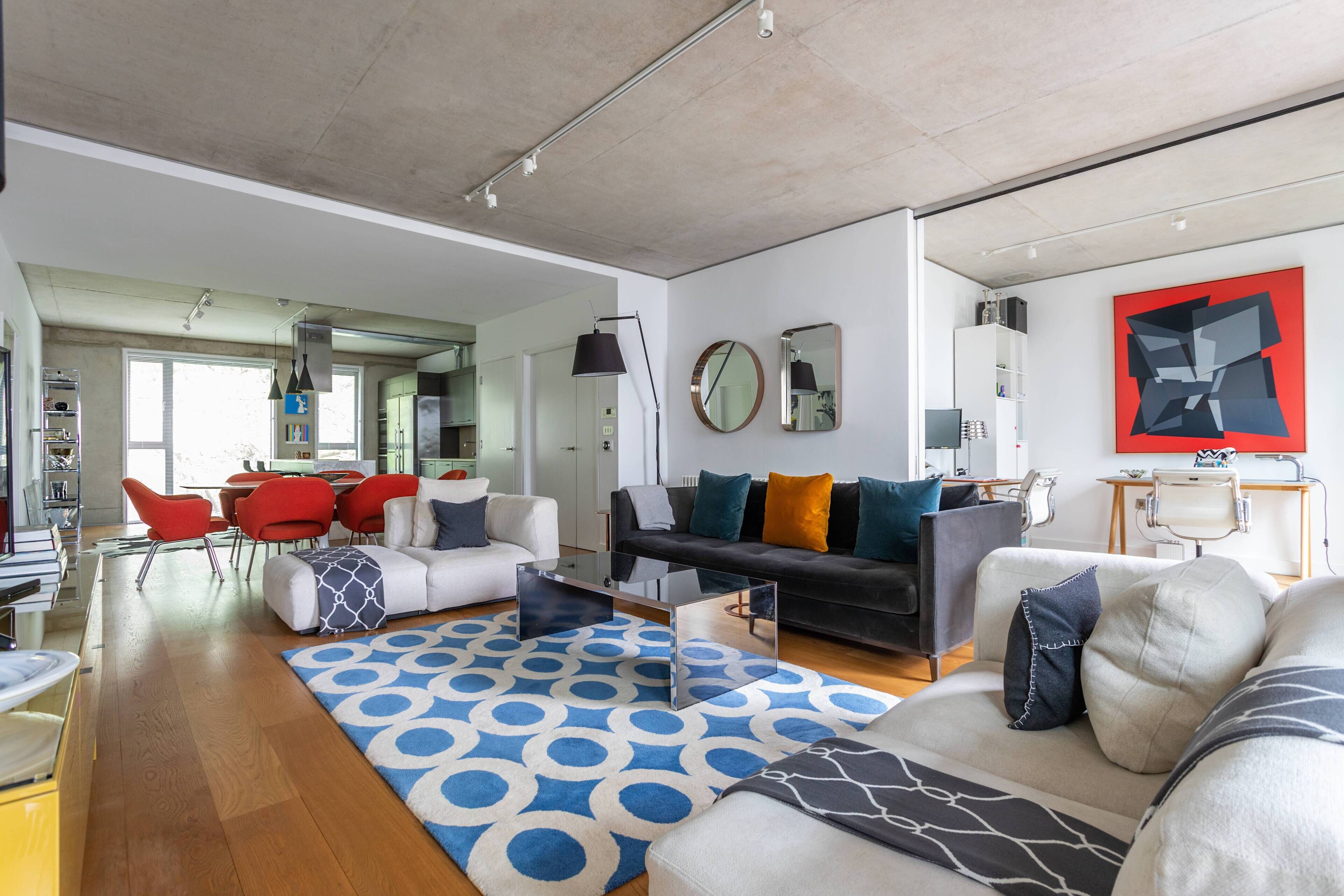 Una sala de estar moderna con un sofá, sillas, una mesa de centro y una alfombra estampada.
