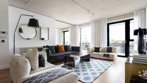 A modern living room with a sofa, armchair, coffee table, and a patterned rug. - Compton Street - Two Bedroom Apartment, Sleeps 4 (London)