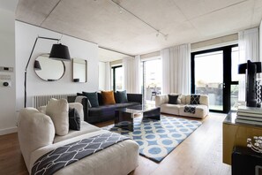 Ein modernes Wohnzimmer mit Sofa, Sesseln, Couchtisch und einem gemusterten Teppich.