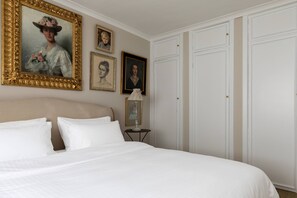 A bedroom with a large bed, a wardrobe, and framed portraits on the wall. - Courtfield Mews - Four Bedroom House, Sleeps 8 (London)