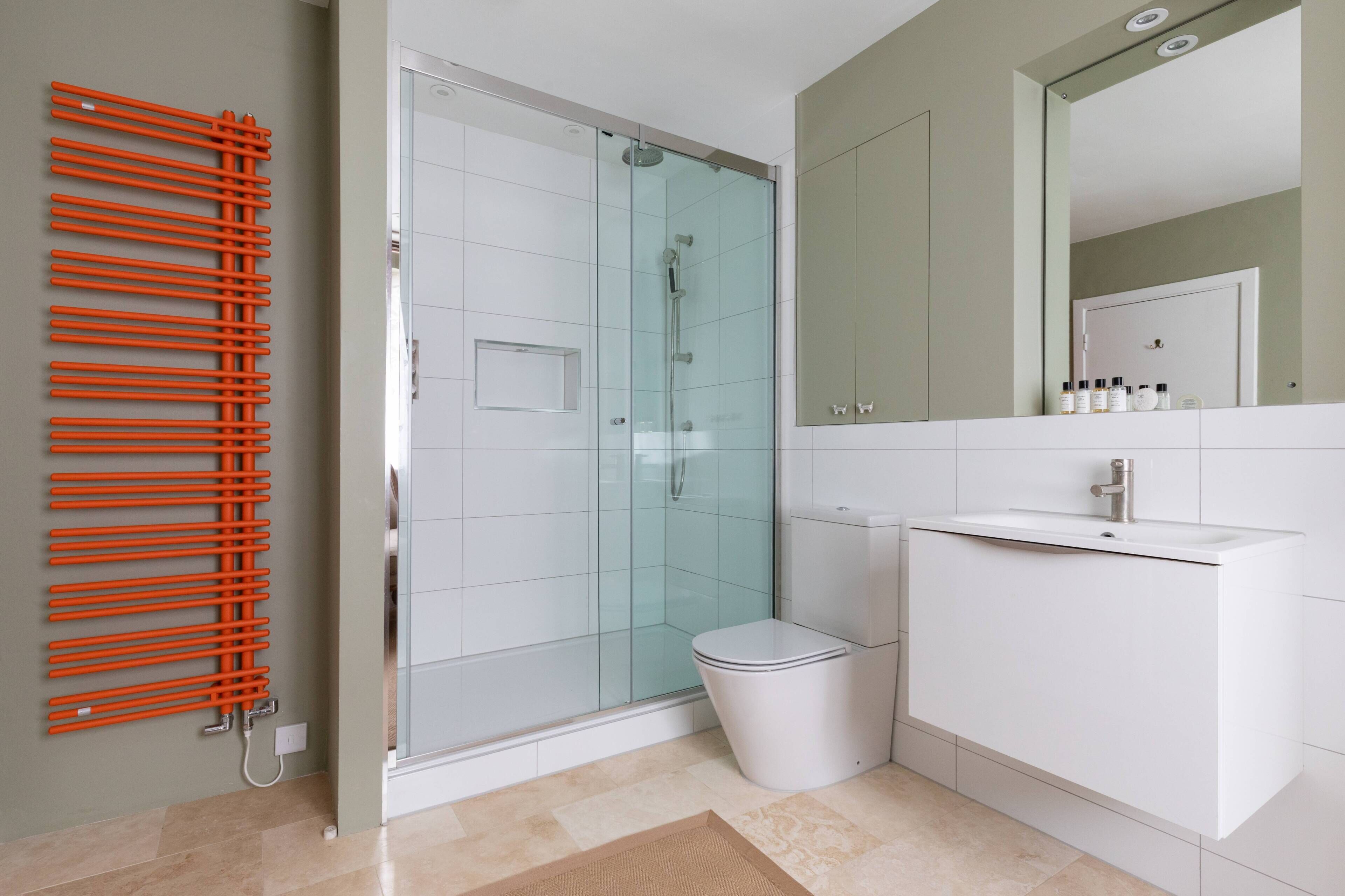 Une salle de bain moderne avec une douche à parois de verre, des toilettes blanches et un lavabo blanc avec un miroir au-dessus.
