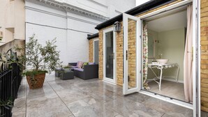 A patio with a sofa, a table, and a potted plant. - Courtfield Mews - Four Bedroom House, Sleeps 8 (London)