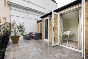 A patio with a sofa, a table, and a potted plant. - Courtfield Mews - Four Bedroom House, Sleeps 8 (London)