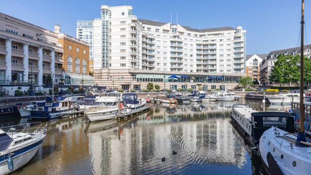 A marina with boats docked, a large hotel building with multiple floors, and a clear sky. - Gertrude Street III - Two Bedroom Apartment, Sleeps 4 (London)