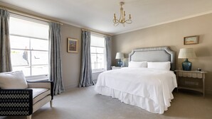A bedroom with a bed, a chair, a nightstand, a lamp, and a chandelier. - Gertrude Street III - Two Bedroom Apartment, Sleeps 4 (London)