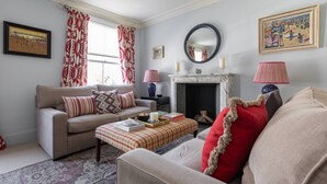 A living room with a sofa, a coffee table, a fireplace, and a painting on the wall. - Gertrude Street III - Two Bedroom Apartment, Sleeps 4 (London)