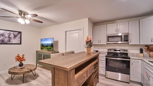 A modern kitchen with a wooden island, stainless steel appliances, and a ceiling fan. - The Ruby 312 (Pigeon Forge)