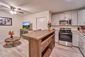 A modern kitchen with a wooden island, stainless steel appliances, and a ceiling fan. - The Ruby 312 (Pigeon Forge)